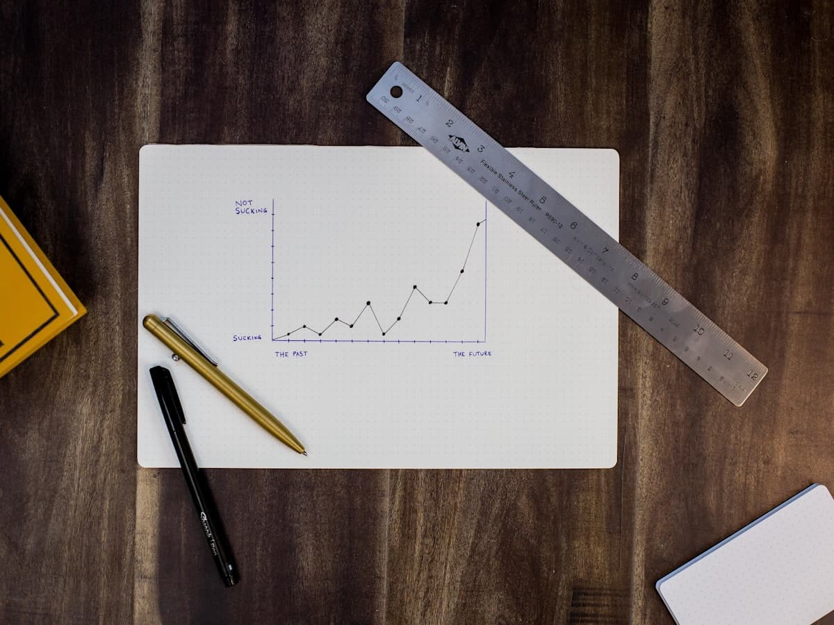 A hand-drawn growth chart on graph paper beside a ruler and two pens