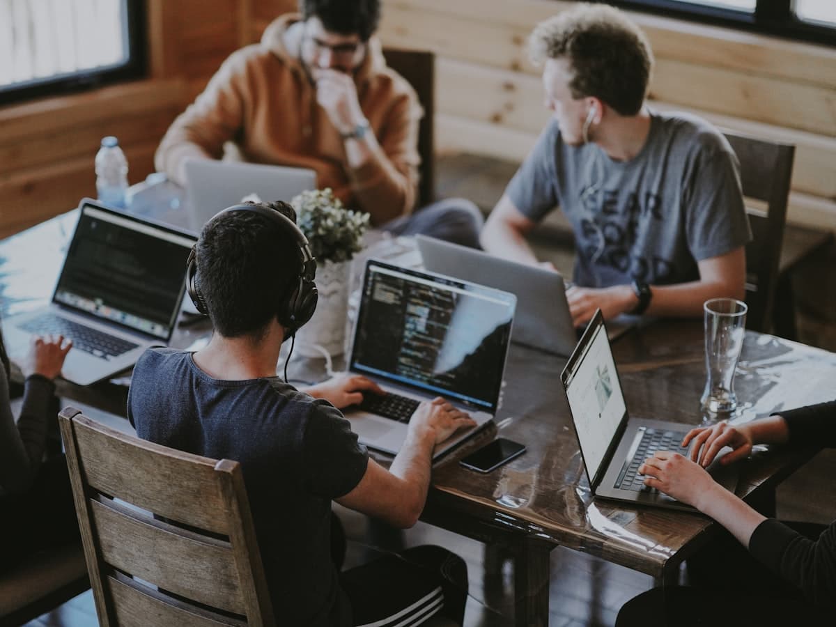A team working side by side at laptops around a wooden table