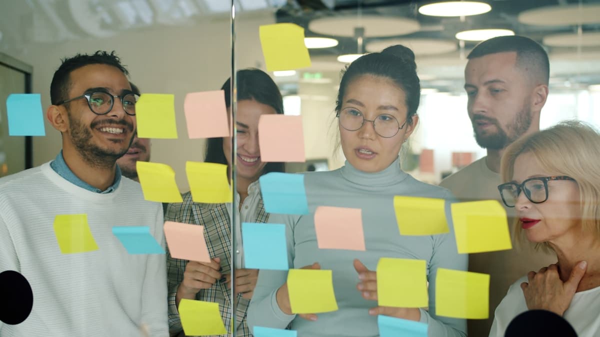 A team working through ideas on a glass wall of sticky notes