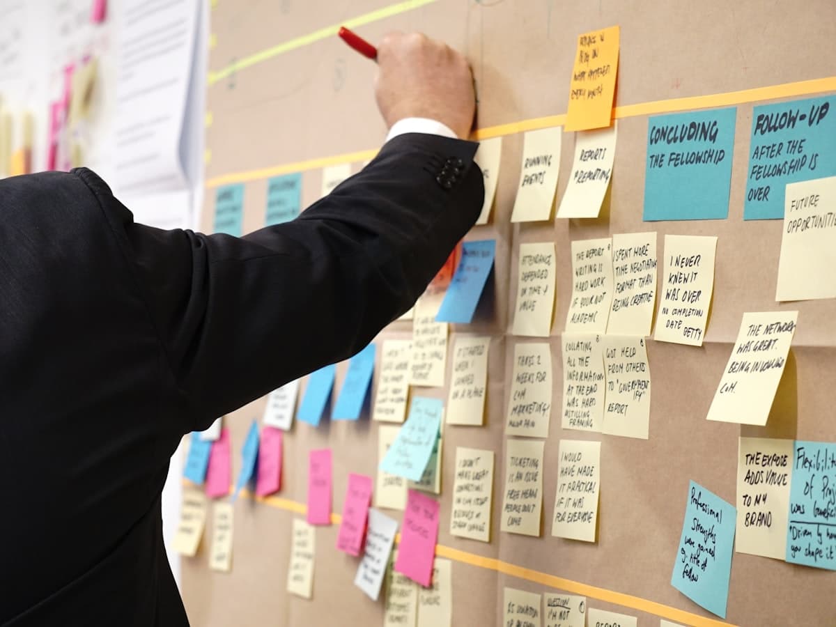 Someone adding a card to a planning wall arranged in labelled columns